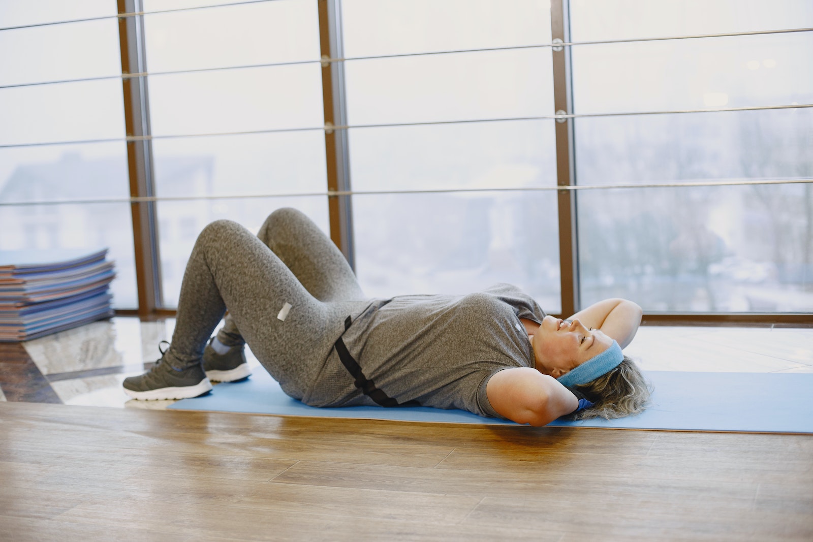 A Woman in Gray Leggings Lying on Floor